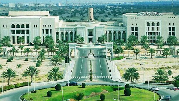 A large, modern building with a central courtyard, surrounded by palm trees and a circular road. - Al Bahjah Hotel (Seeb)