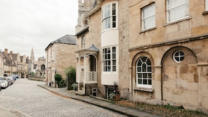 A cobblestone street lined with historic stone buildings, featuring arched windows and a traditional architectural style. - Crown Hotel Stamford (Stamford)