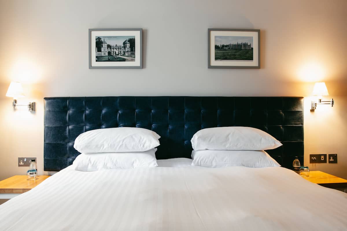 Een hotelkamer met een groot bed, twee ingekaderde foto's aan de muur en bedlampjes.