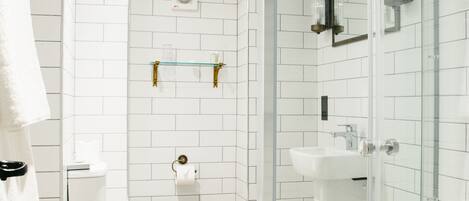 Un baño moderno con cabina de ducha de vidrio, inodoro blanco y lavamanos.