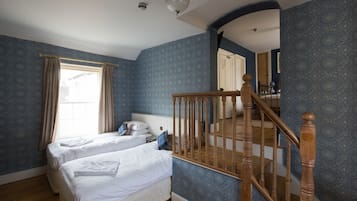 Un dormitorio con dos camas, una escalera de madera y un ventanal con cortinas.