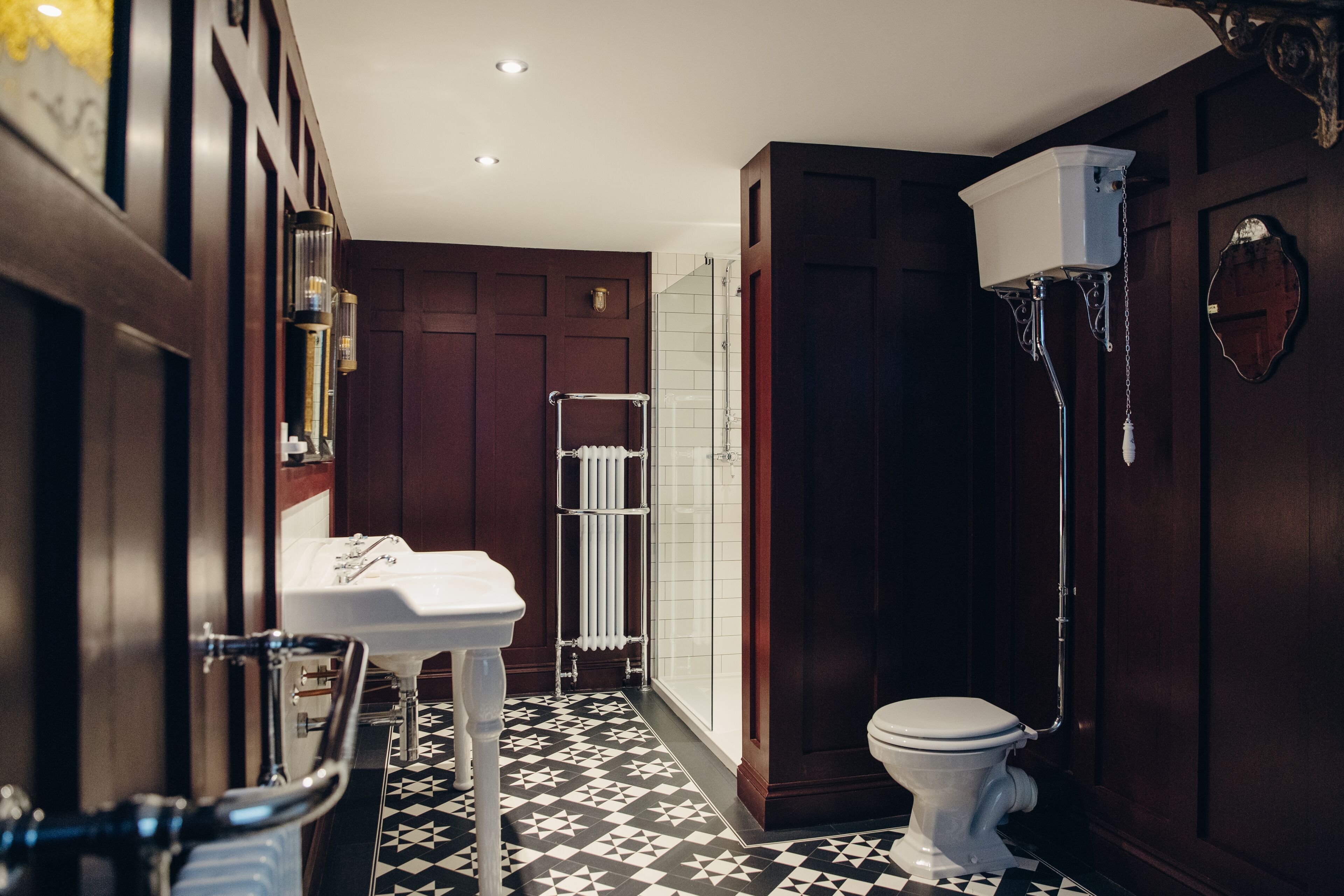 A bathroom with a white toilet, a white sink, a glass shower enclosure, and a radiator.
