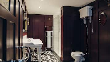 A bathroom with a white toilet, a white sink, a glass shower enclosure, and a radiator.
