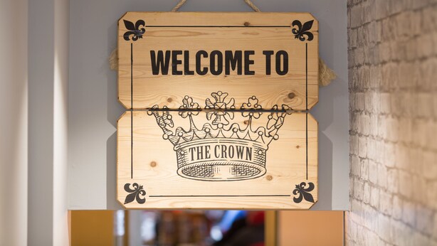 A wooden sign with "WELCOME TO THE CROWN" hanging on a wall. - Crown Hotel Stamford (Stamford)