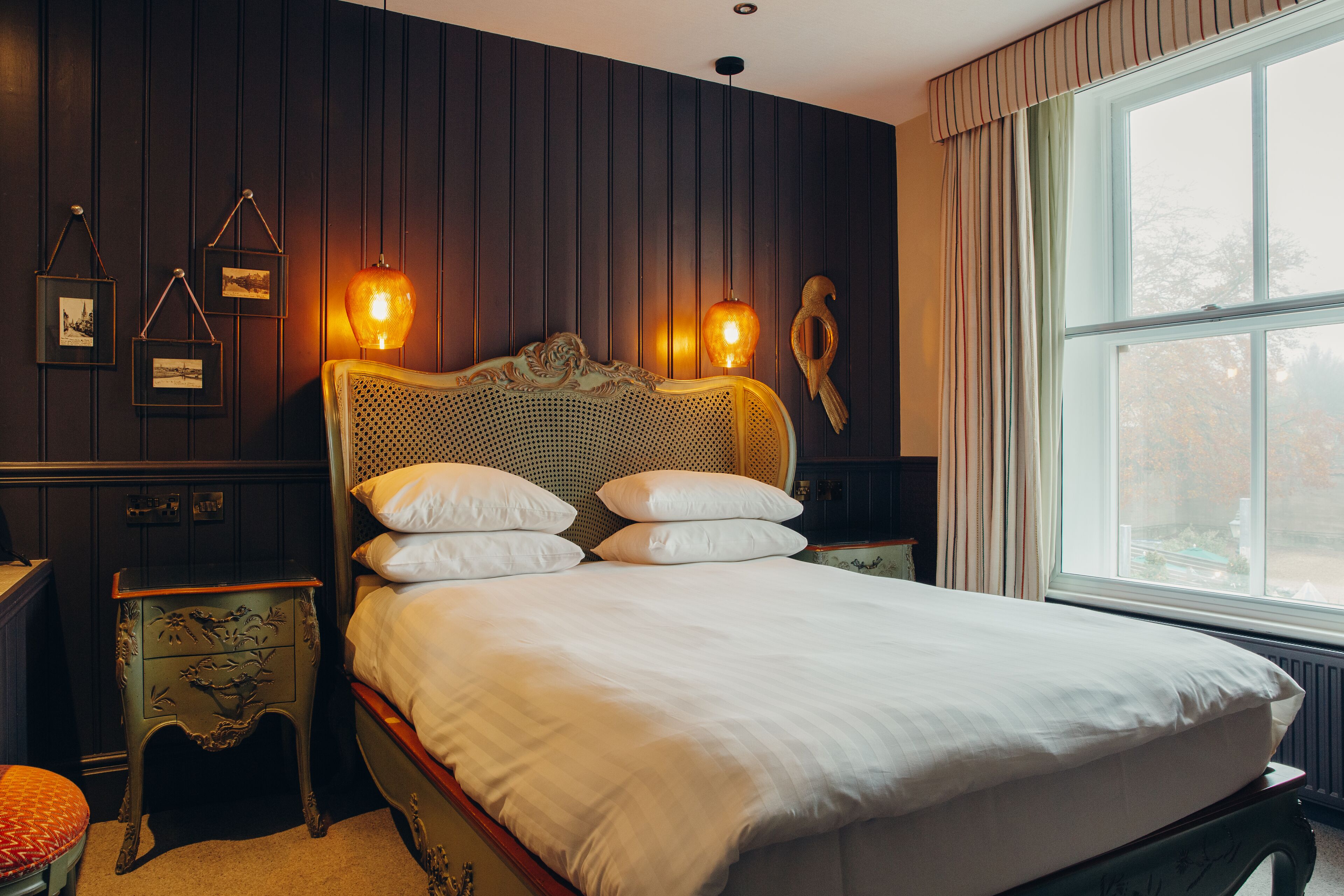 A bedroom with a large bed, wooden headboard, and a window with curtains.