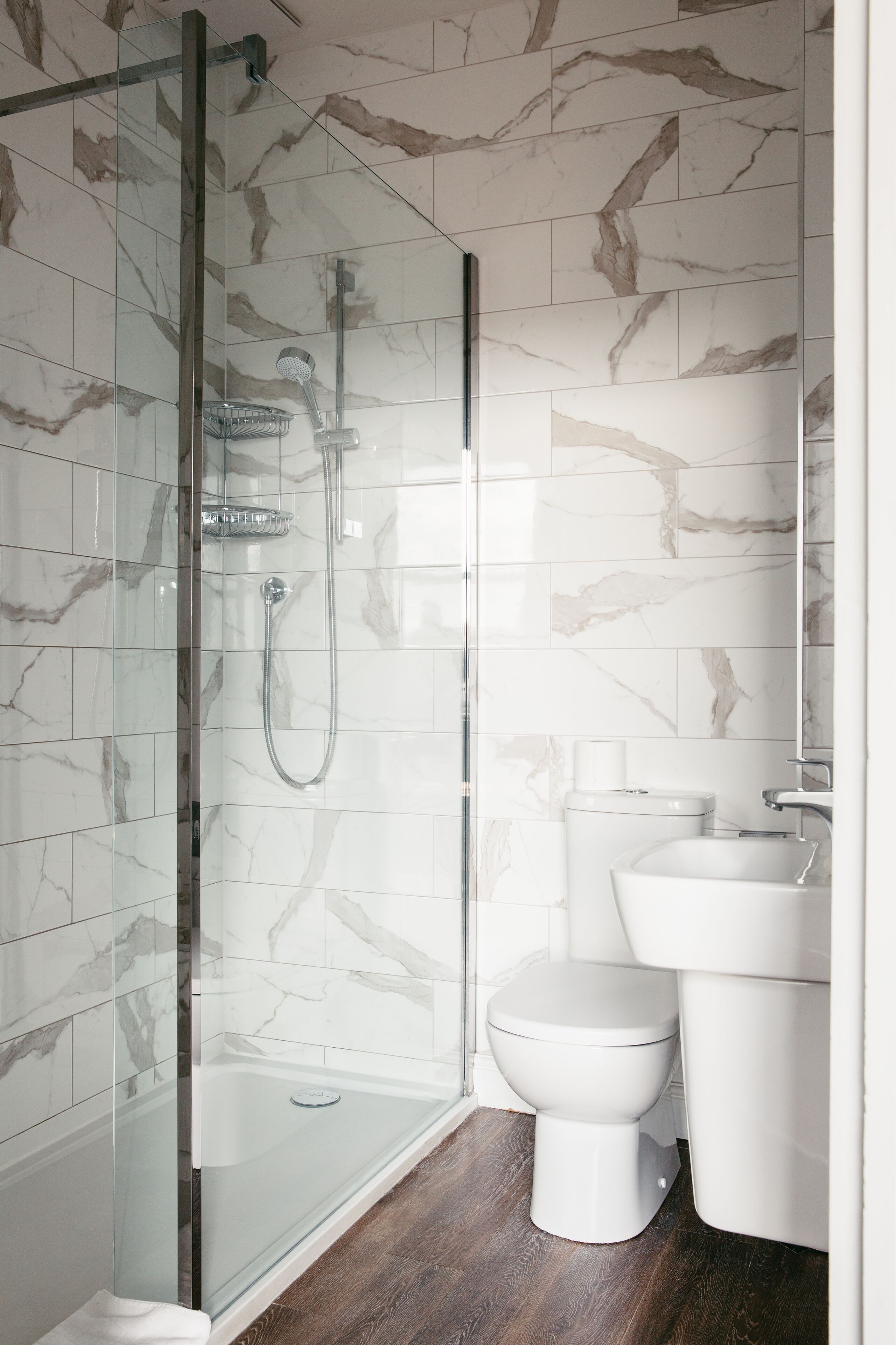 A modern bathroom with a glass-enclosed shower, a white toilet, and a sink.