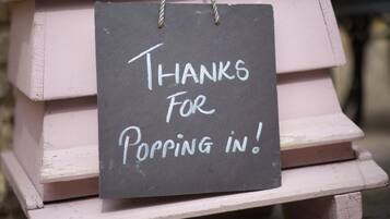 A chalkboard sign with the text "Thanks For Popping In!" hanging on a wooden structure.