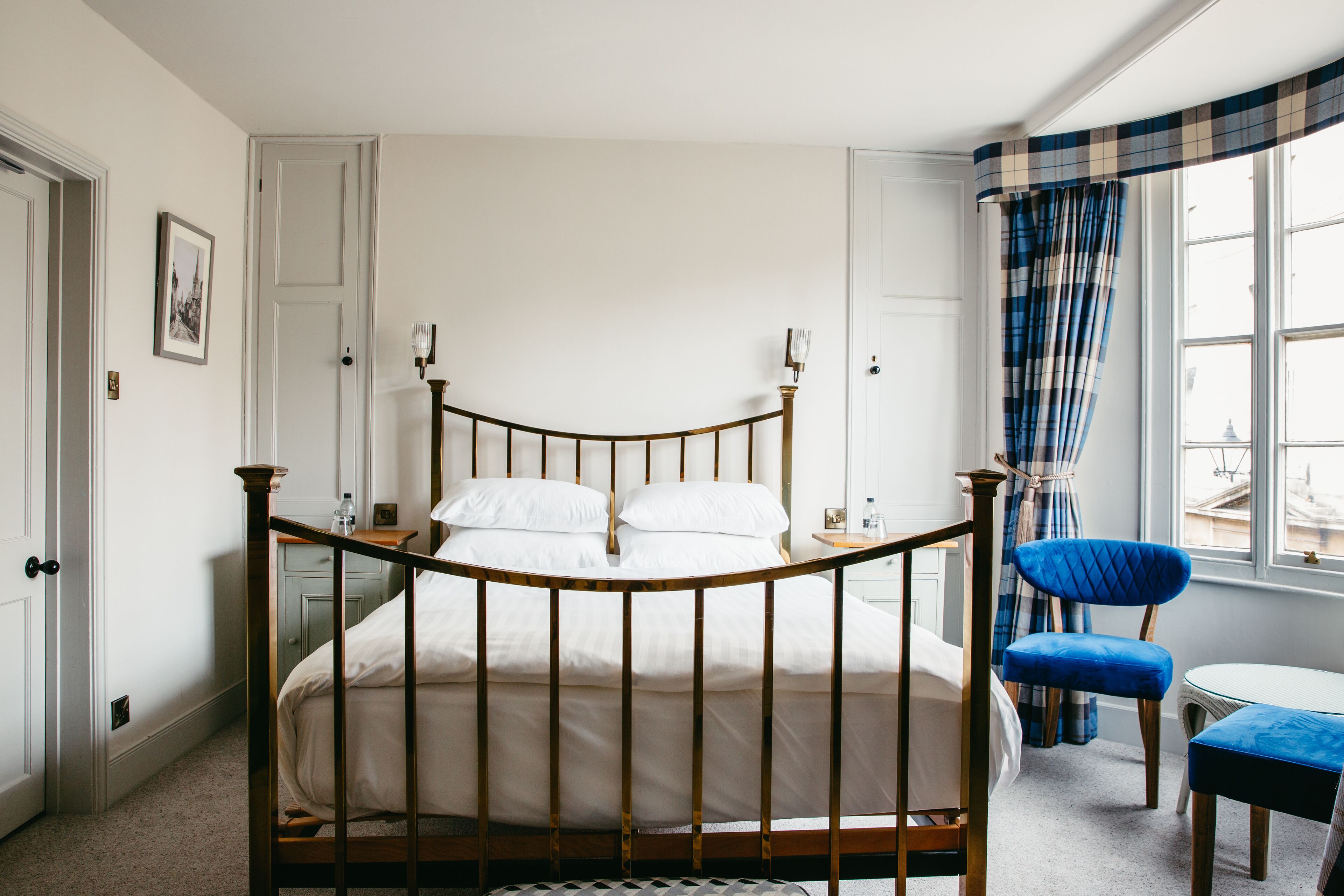 A neatly arranged bedroom with a wooden bed, a chair, a small table, and a window with curtains.