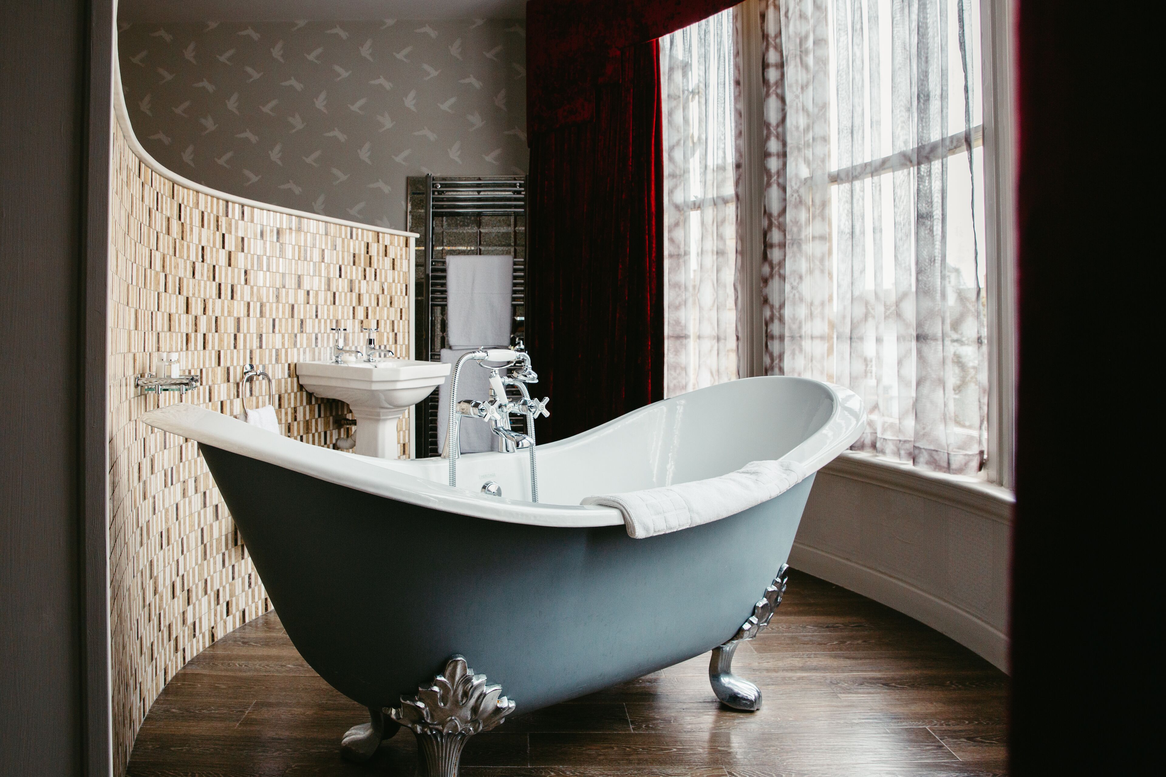 A bathroom with a freestanding bathtub, a sink, and a mirror.