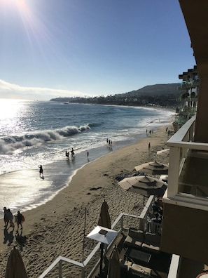Une plage où l’on voit des gens se promener le long du rivage, des parasols et une vue sur l’océan.