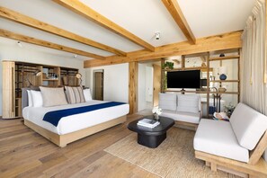 A modern bedroom with a large bed, a sofa, a coffee table, and built-in wooden shelving. - Pacific Edge Hotel (Laguna Beach)