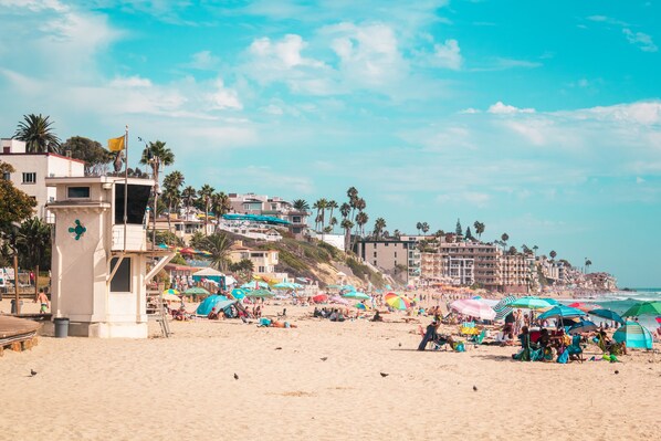 A beach with a lifeguard tower, umbrellas, and people.