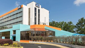 A modern building with a blue and orange facade, large windows, and a clear sky. - Howard Johnson by Wyndham Williamsburg (Williamsburg)