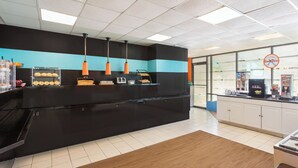 A modern kitchen with a black countertop, orange pendant lights, and a blue stripe on the wall. - Howard Johnson by Wyndham Williamsburg (Williamsburg)