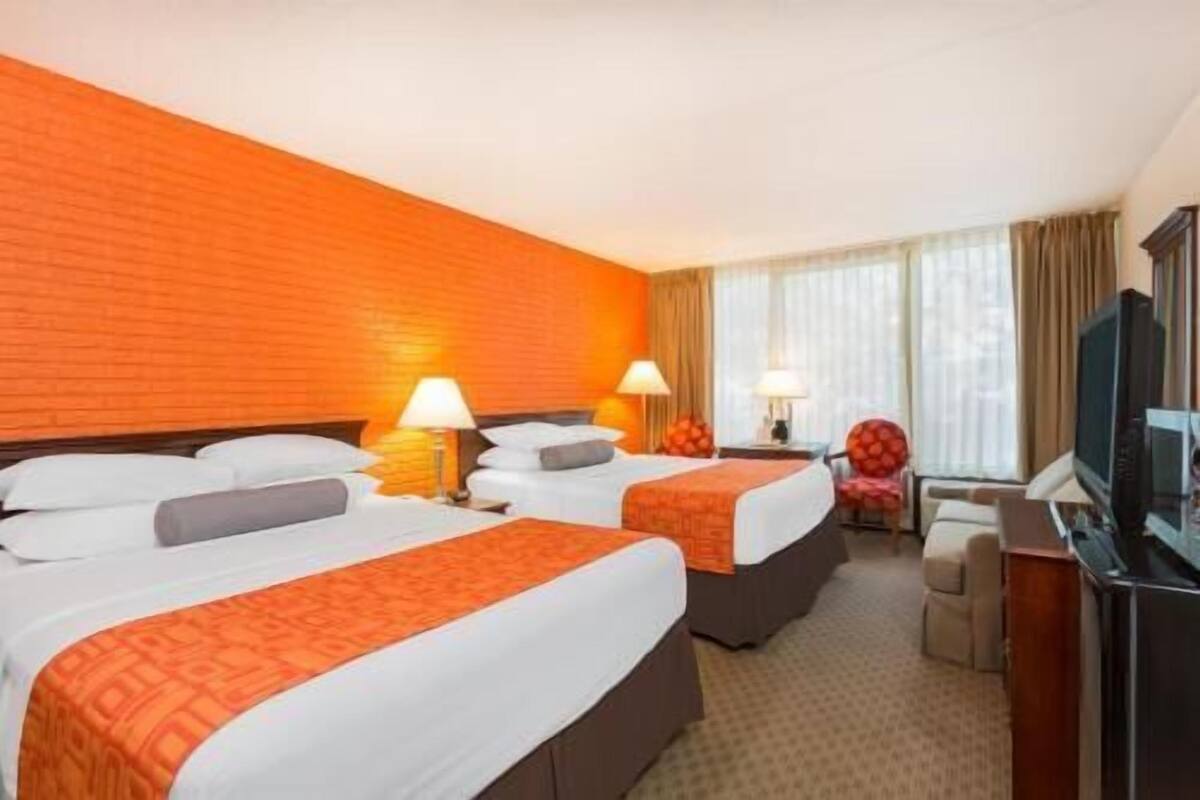 Habitación de hotel con dos camas, televisión y escritorio.