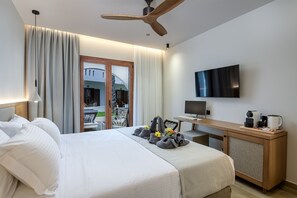 A hotel room with a bed, a desk with a TV, a ceiling fan, and a view of the outside. - Gaia Garden (Kos)