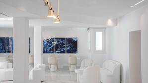 Una habitación moderna y minimalista con muebles blancos, un cuadro abstracto grande y vistas al exterior.