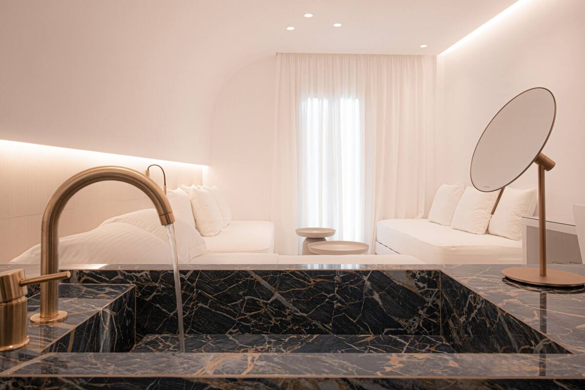 A modern bathroom with a marble sink, gold fixtures, and a large mirror.