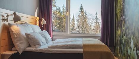 Un dormitorio con una cama, dos lámparas de noche, una ventana con cortinas y un cuadro en la pared.