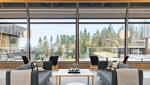 A modern interior with a sofa set, a table, and large windows offering a view of trees and a building. - Voksenasen Hotell, BW Signature Collection (Oslo)