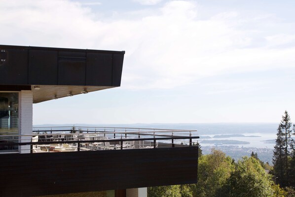 A modern building with a balcony overlooking a scenic view of a body of water and distant land. - Voksenasen Hotell, BW Signature Collection (Oslo)