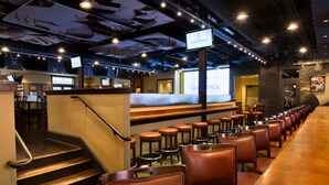 A restaurant interior with a bar area, seating, and a staircase leading to another level.