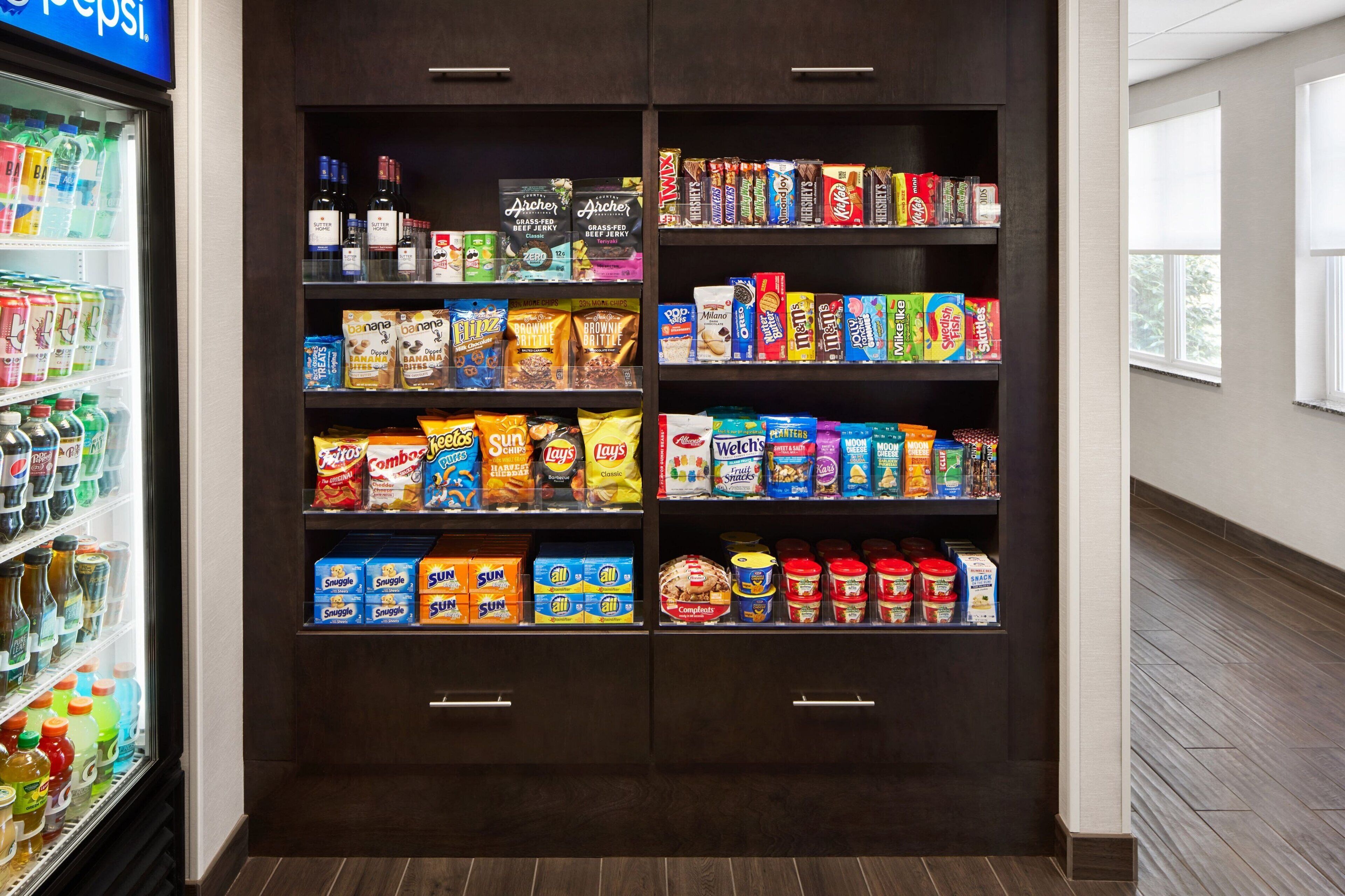 A snack and beverage display in a hotel lobby with various snacks, cereals, and beverages.