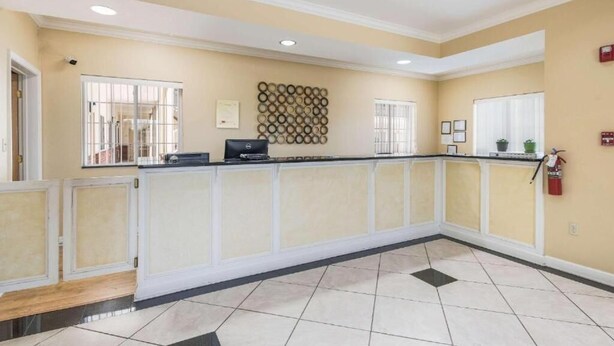 A reception area with a counter, a wall-mounted decorative item, and a fire extinguisher. - Bryant Inn & Suites (Bryant)