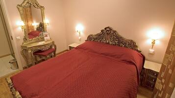 A bedroom with a large bed, a dresser, a mirror, and two wall sconces.