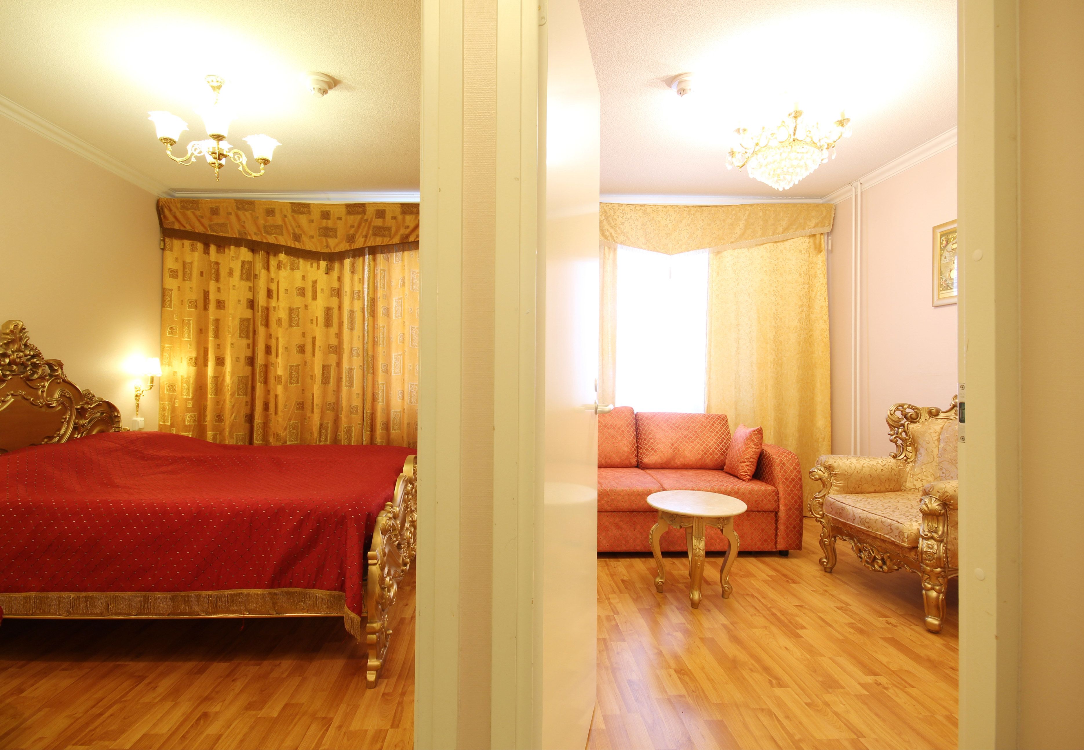 A hotel room with a bed, a sofa, a small table, and a chair.