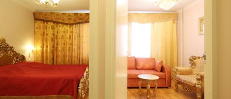 A hotel room with a bed, a sofa, a small table, and a chair.