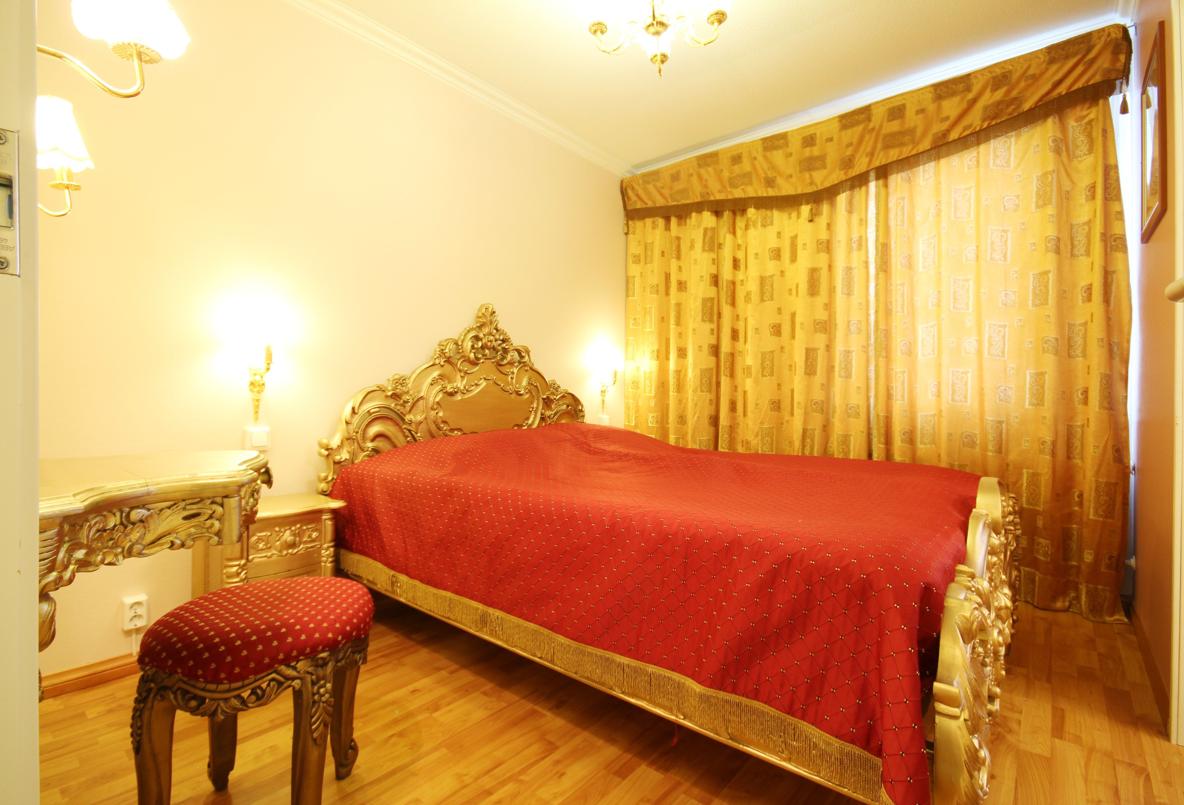 A room with a large bed, a wooden chair, a nightstand, and a lamp.