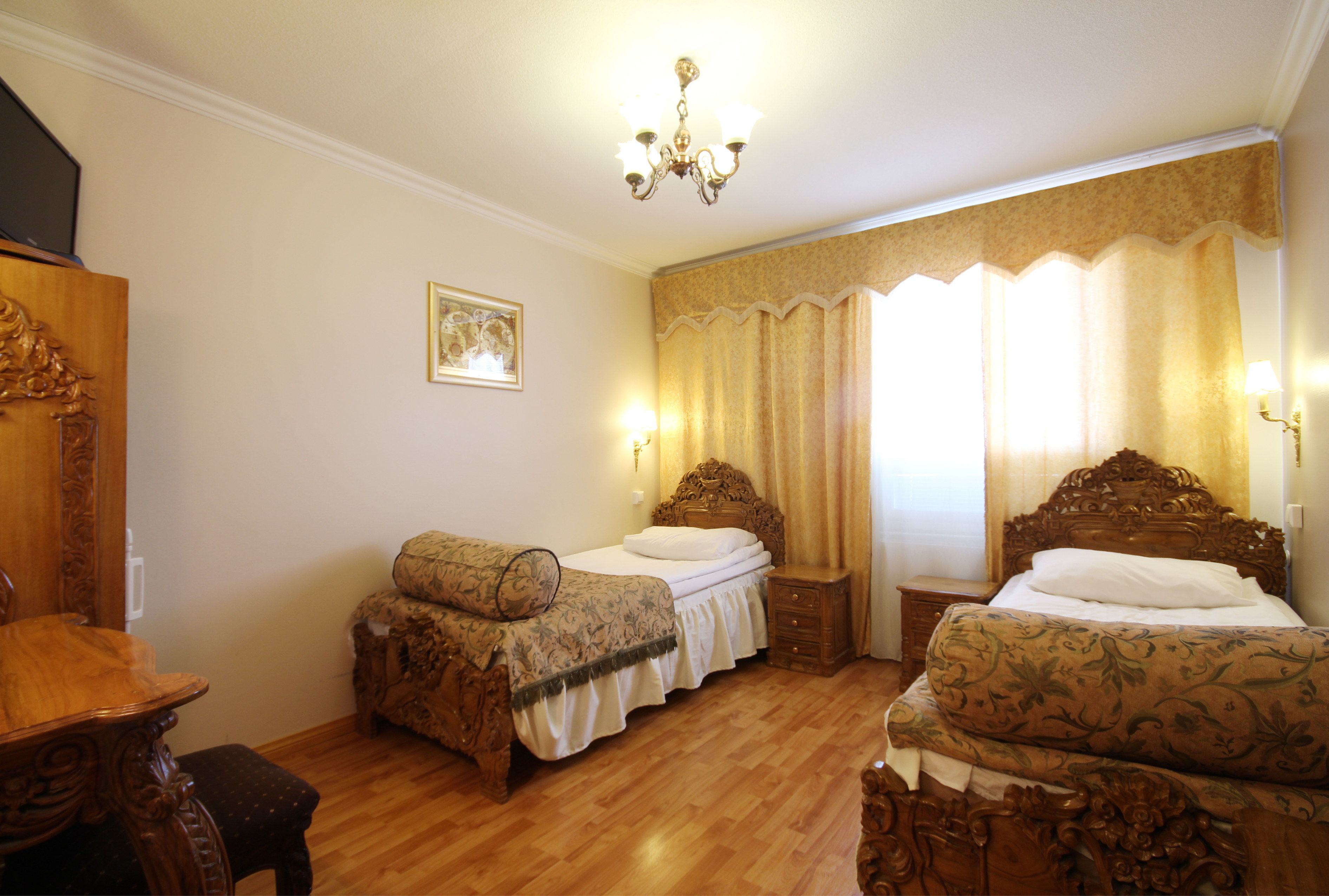 Une chambre à coucher avec deux lits en bois, une commode en bois, une table de chevet et un lustre.