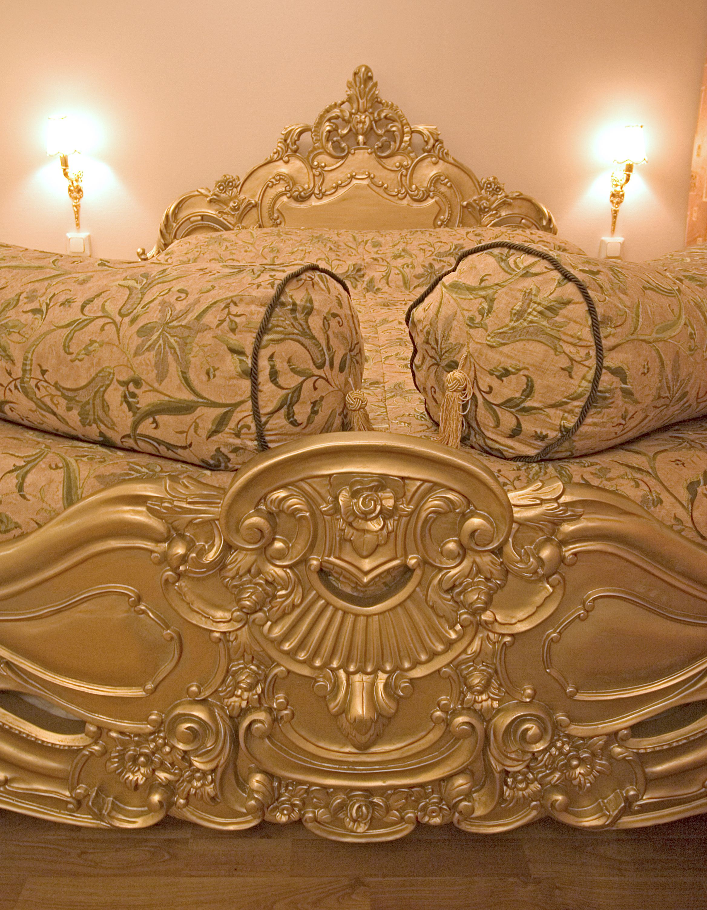 A bed with an ornate headboard and floral patterned bedding.