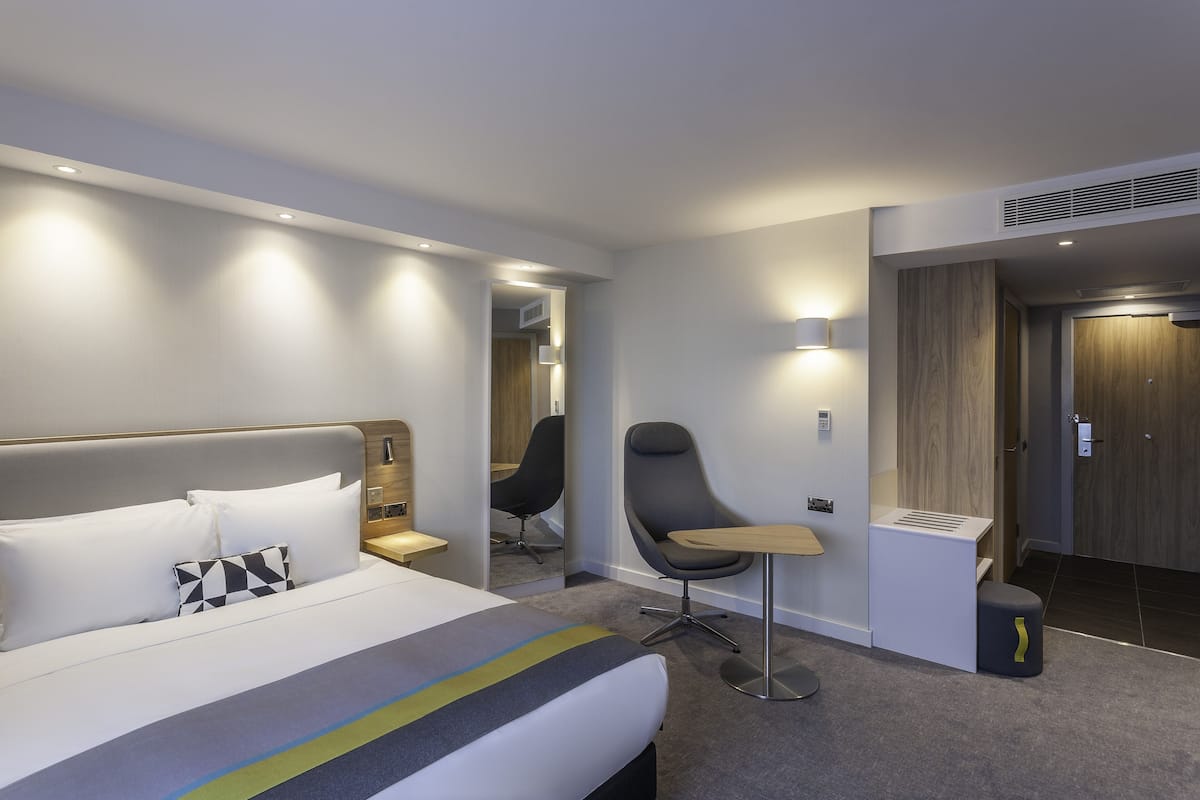 Une chambre d’hôtel moderne dotée d’un grand lit, d’un bureau, d’une chaise et d’une salle de bain séparée.