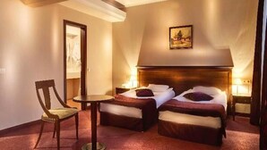 Une chambre d’hôtel avec deux lits, une chaise, une petite table et un tableau au mur.