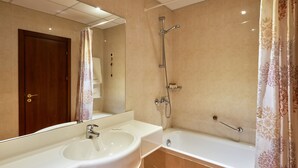 Une salle de bain équipée d’un lavabo, d’un miroir, d’une douche et d’une baignoire.
