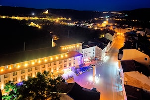 A hotel with multiple floors, a parking area, and a view of the surrounding town.