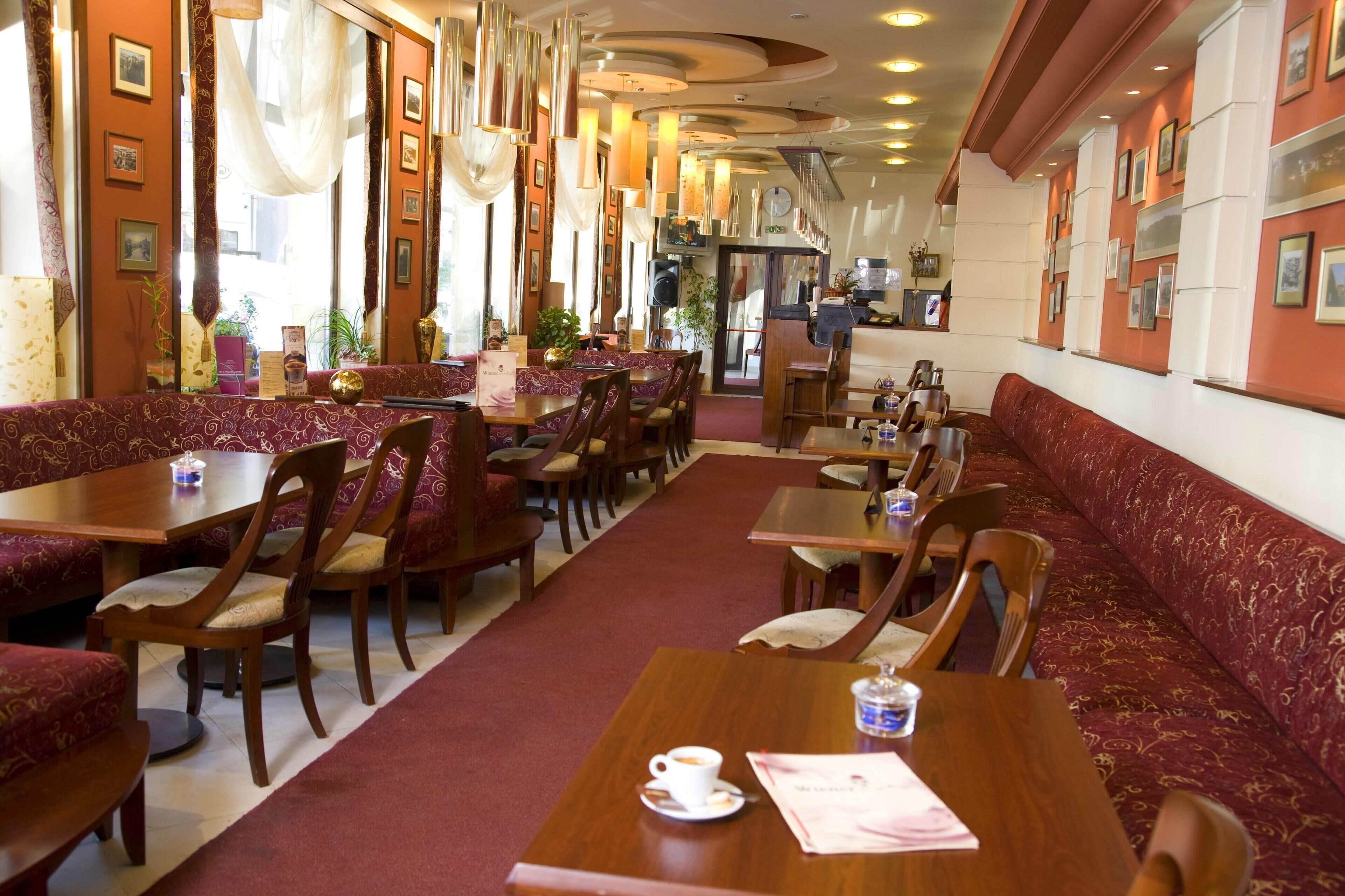 A restaurant with wooden tables and red upholstered booths, featuring a carpeted floor and framed pictures on the walls.
