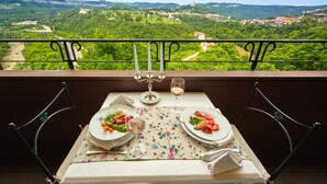 A balcony table with a tablecloth, two plates with food, a wine glass, and a candle. - Yantra Grand Hotel -sharlopov Hotels (Veliko Tarnovo)