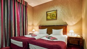 Une chambre d’hôtel avec deux lits, un grand tableau au mur et une moquette rouge.