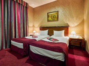 Una camera d'albergo con due letti, un grande quadro appeso al muro e un tappeto rosso.