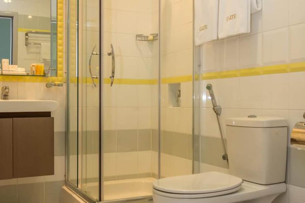 A modern bathroom with a glass-enclosed shower, a toilet, and a sink.