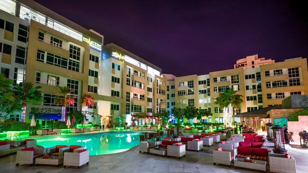 A hotel with a swimming pool, outdoor seating, and a well-lit facade. - Elite Seef Residence & Hotel (Manama)