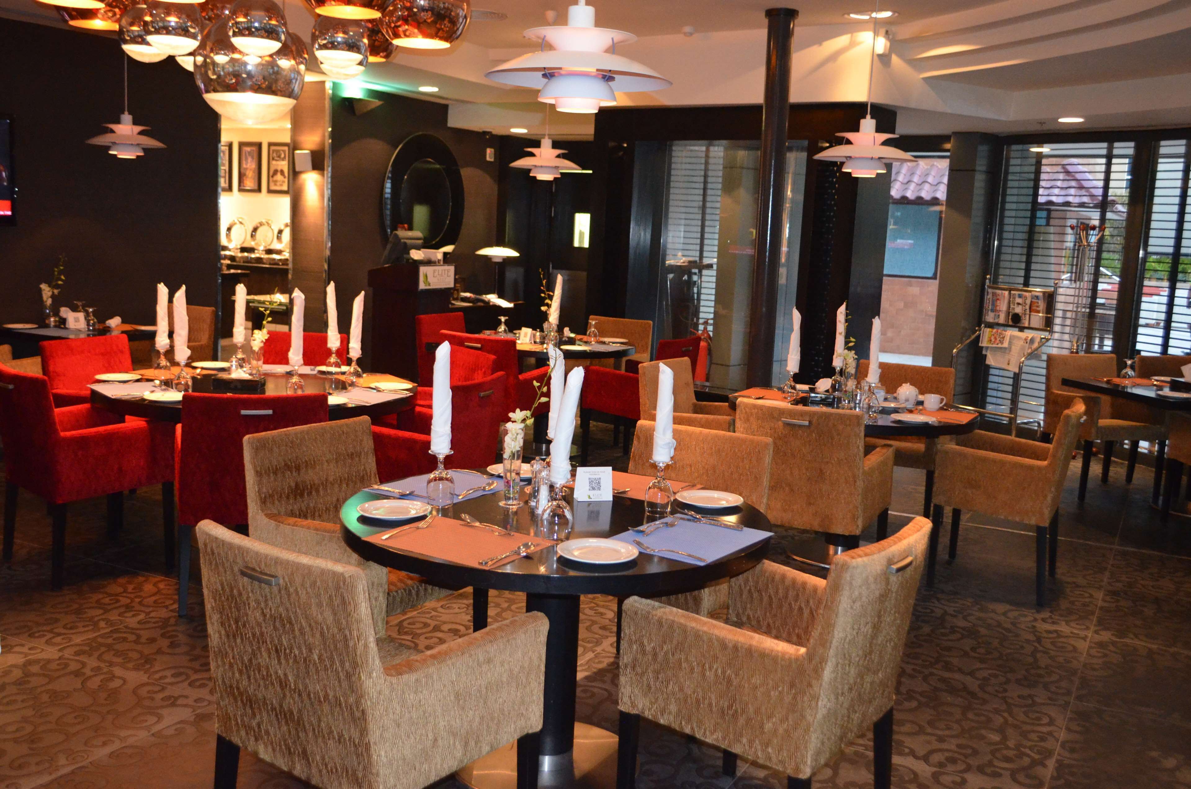 A restaurant with round tables, red chairs, and white candles.
