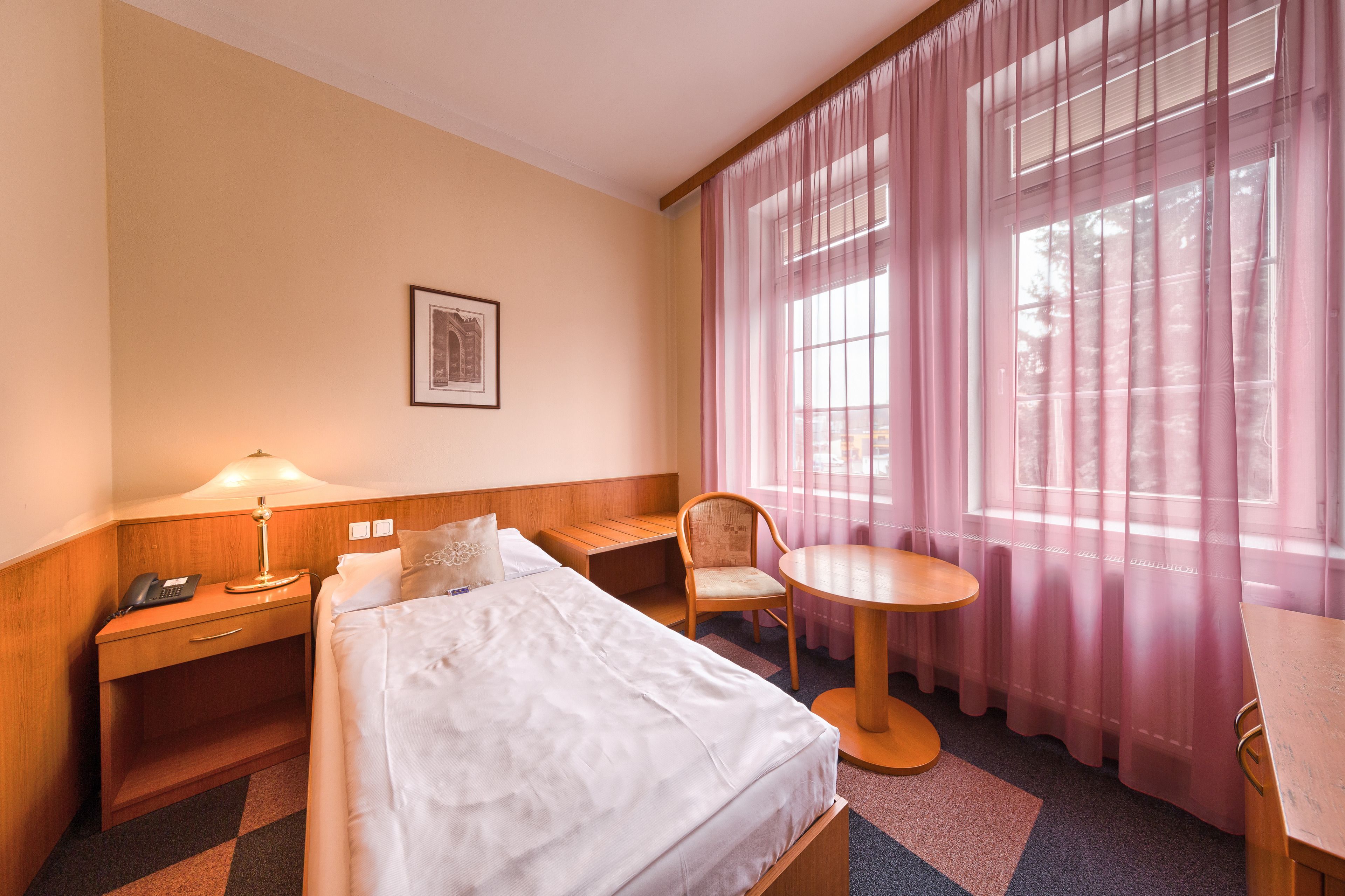 Une chambre d’hôtel comprenant un lit, une table de chevet, une lampe, une chaise et une petite table ronde.