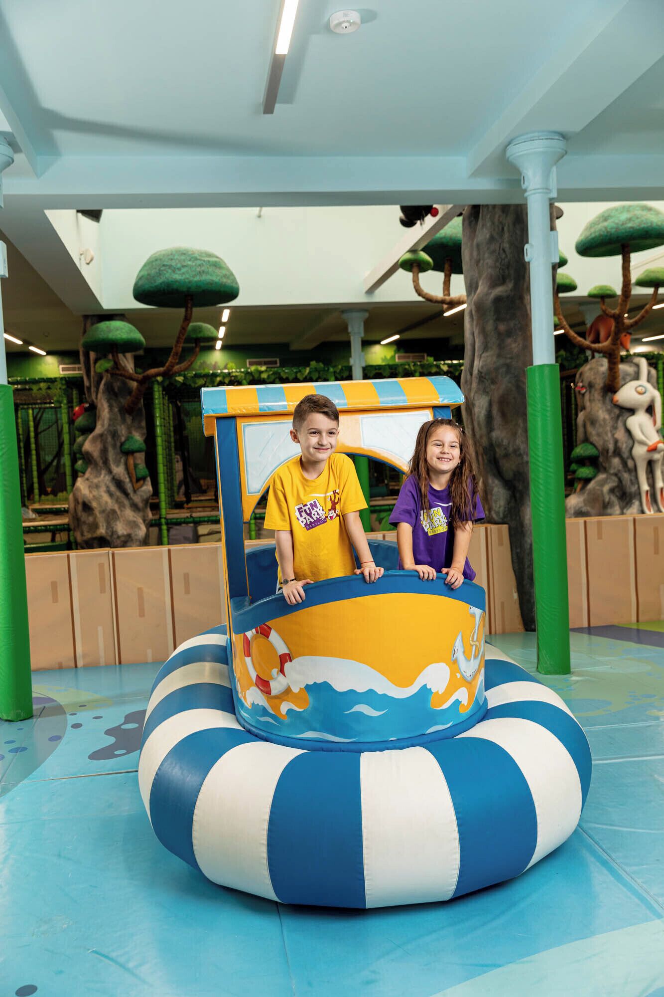 Two children in a play area with a blue and white inflatable boat.