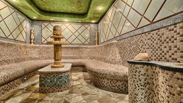 A spa area with mosaic tiled walls, a stone floor, and a central column.