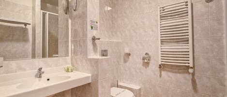 Un baño moderno con lavamanos, inodoro y perchero para toallas.