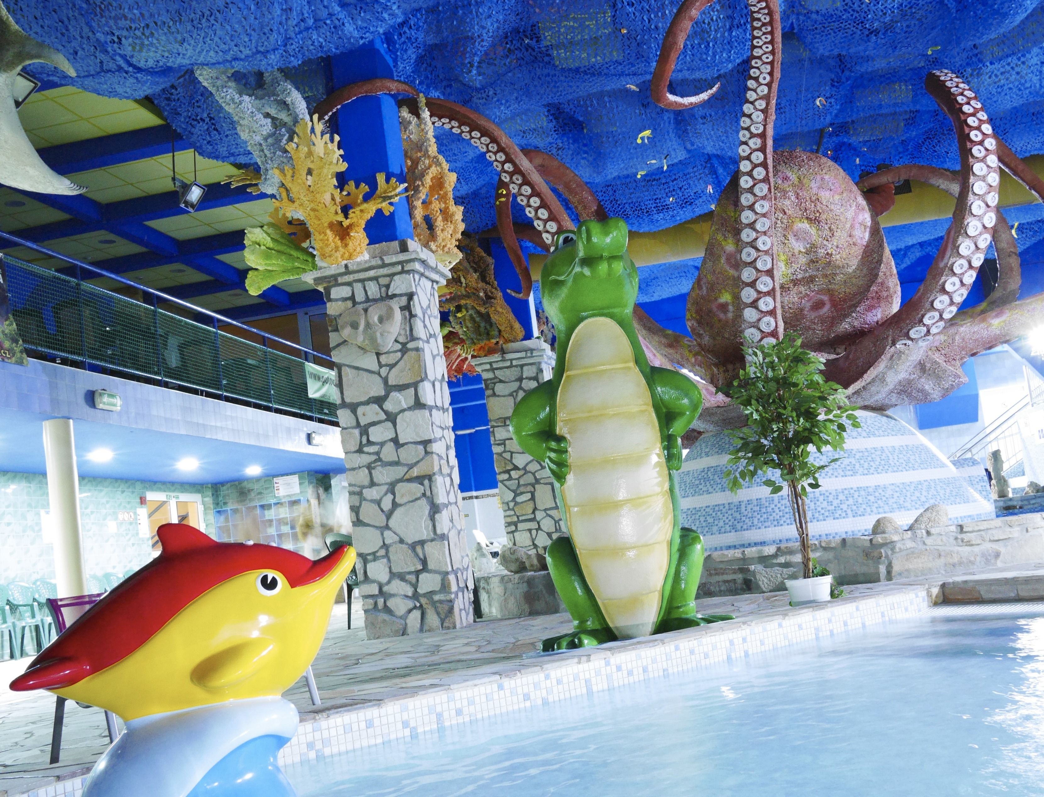 Un área de piscina con una gran escultura de pulpo, una estatua de cocodrilo y una escultura de pez colorido.